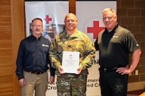 Dan Williams, executive director of the American Red Cross serving northern and central Minnesota, Tech. Sgt. Jared Hinks, a munitions systems specialist with the 148th Fighter Wing, and Jeff Kazel, regional director of the American Red Cross Service to the Armed Forces for Minnesota and the Dakotas, pose for a photo at the 148th Fighter Wing in Duluth, Minn., Sept. 22, 2025.