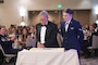 Retired Airman and Airman cut a cake during a ceremony.