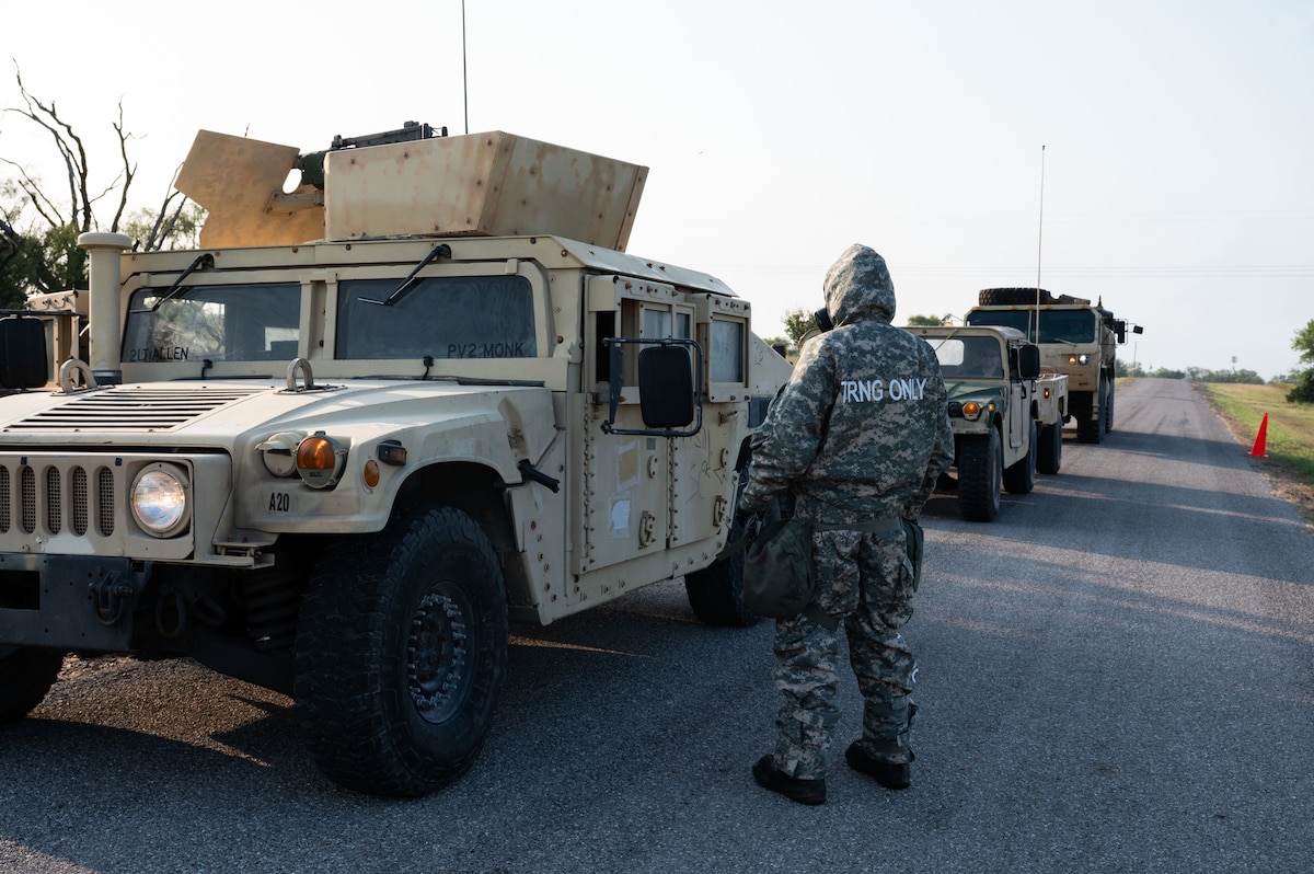 An Airman from Altus Air Force Base’s 97th Civil Engineer Squadron, Readiness and Emergency Management Flight stops a U.S. Army vehicle to explain the decontamination process during an exercise at Fort Sill, Oklahoma, September 7, 2025. During the exercise, Soldiers from the 3-2 Air Defense Artillery Battalion simulated exposure to an unknown Chemical, Biological, Radiological, and Nuclear agent. This forced them to rapidly break down their camp and move all personnel and equipment through a decontamination line before establishing a new position. (U.S. Air Force photo by Tech. Sgt. Hailey Haux)