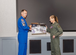 Space Force Guardian and NASA Astronaut Brig. Gen. Nick Hague presents a Space Force flag to the U.S. Test Pilot School commandant, Col. Maryann Karlen, that was flown aboard Crew-9 Dragon Freedom and the International Space Station Expedition 71/72 during a 171-day journey traveling over 72 million miles. (Photo Lindsey Iniguez)