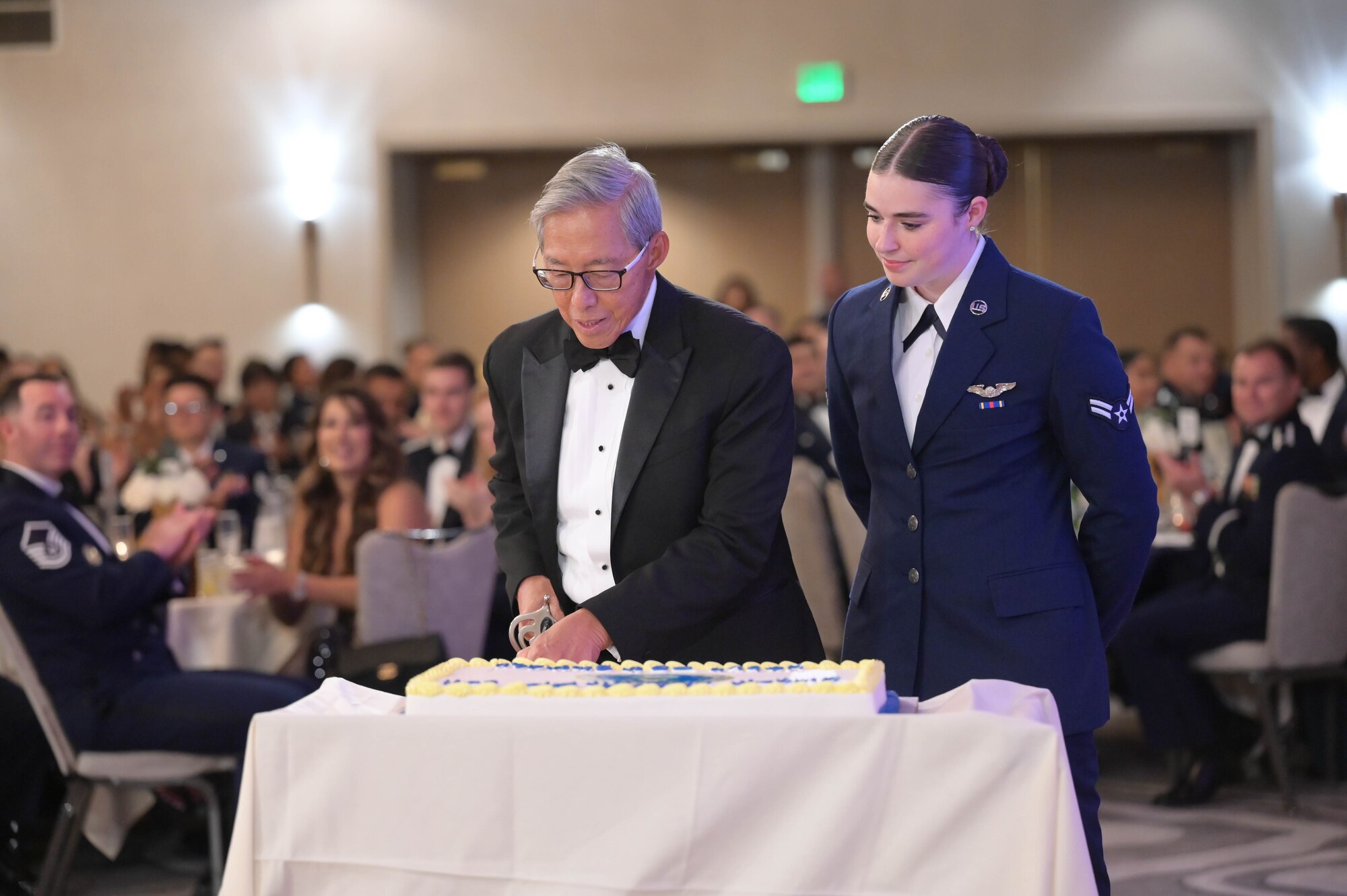 Retired Airman and Airman cut a cake during a ceremony.
