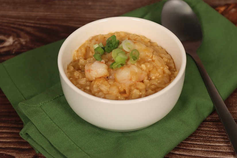 A bowl is filled with a porridge-like substance and shrimp.