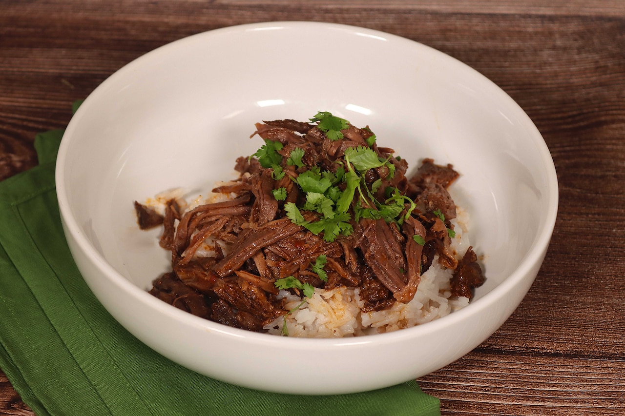 A bowl is filled with rice and shredded beef.