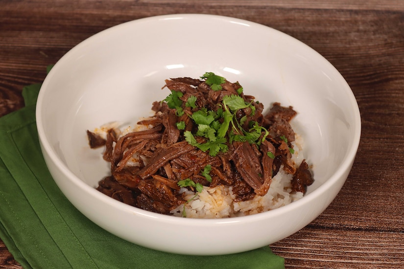A bowl is filled with rice and shredded beef.