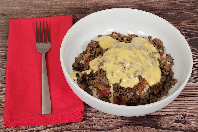 A bowl is filled with ground beef and rice and covered in melted cheese.