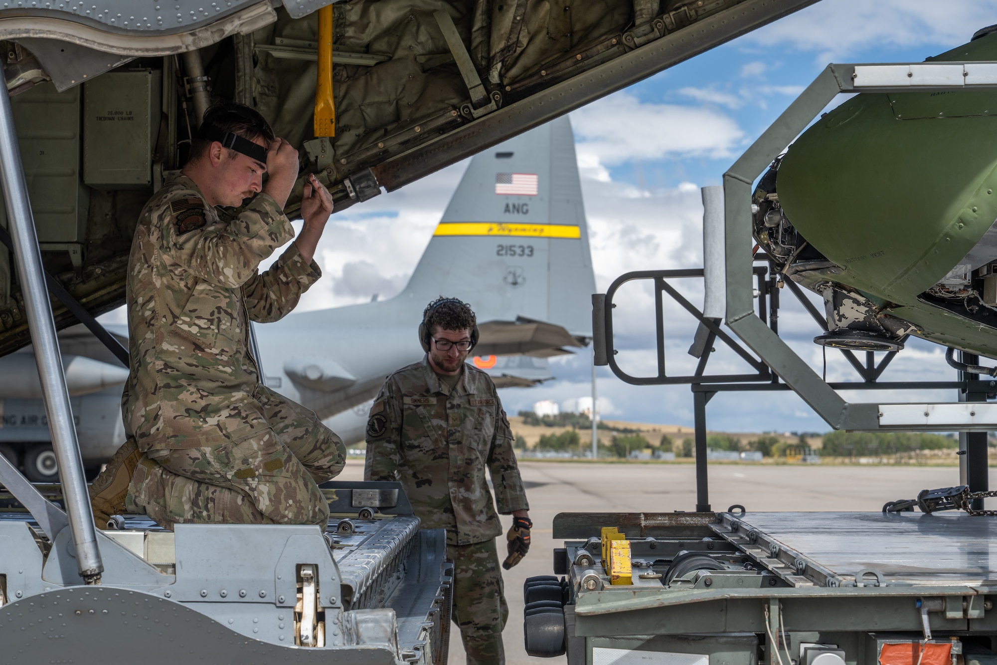 U.S. Air Force Senior Airman  Cory McCloskey, 39th Airlift Squadron instructor loadmaster, and Senior Airman Tyler Simmers, 90th Logistics Readiness Squadron air terminal operator, directs the tail section of a UH-1 helicopter onto the cargo area of a C-130J Super Hercules from the 317th Airlift Wing at Wyoming Air National Guard Base in Cheyenne, Wyo., Sept. 17, 2025. The helicopter, previously assigned to the 90th Missile Wing at F.E. Warren Air Force Base in Cheyenne, was transported by the 317th AW to the 436th Training Squadron’s crash lab at Dyess Air Force Base, Texas. (U.S. Air Force photo by Airman 1st Class Caleb Schellenberg)
