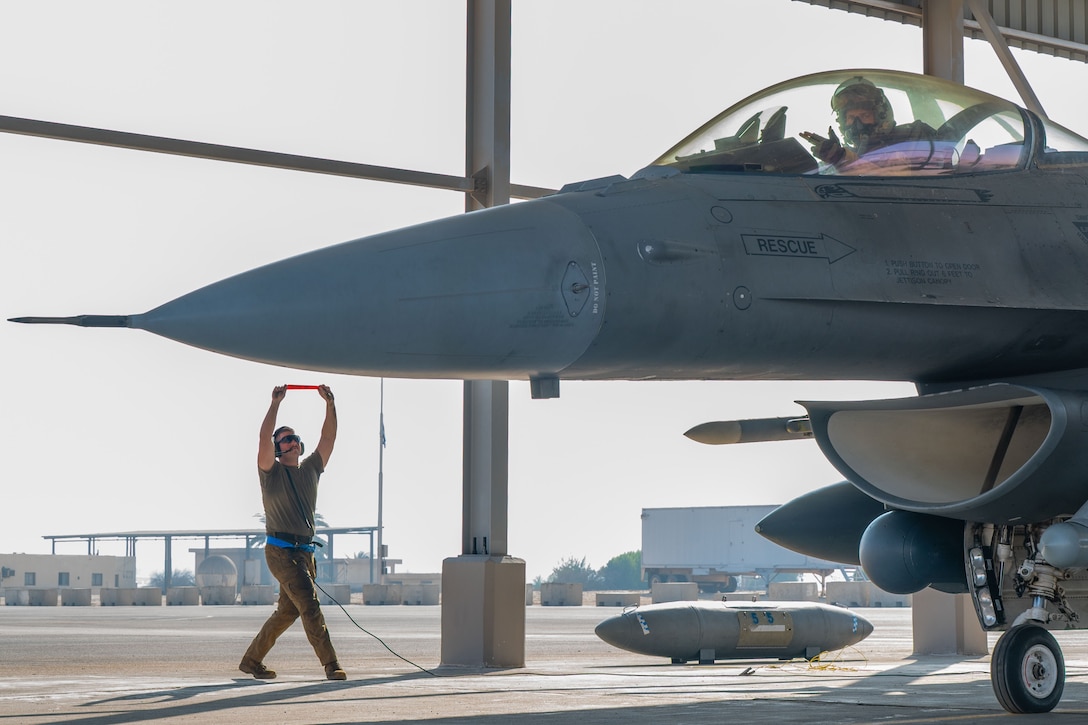U.S. Air Force Senior Airman Thomas Heester, 55th Expeditionary Fighter Generation Squadron dedicated crew chief, removes a pre-flight safety pin, while Capt. Nathan Feldmann, 55th Expeditionary Fighter Squadron pilot, displays the squadron’s ‘Shooters’ hand gesture, before a Composite Air Operation with partner nations during BRIGHT STAR 25 at Cairo West Air Base, Egypt, Aug. 30, 2025. The United States is one of over 40 countries participating in BRIGHT STAR 25, a multilateral U.S. Central Command exercise held with the Arab Republic of Egypt across air, land and sea domains that promotes and enhances regional security and cooperation and improves interoperability in irregular warfare against hybrid threat scenarios. (U.S. Air Force photo by Staff Sgt. Kevin Dunkleberger)