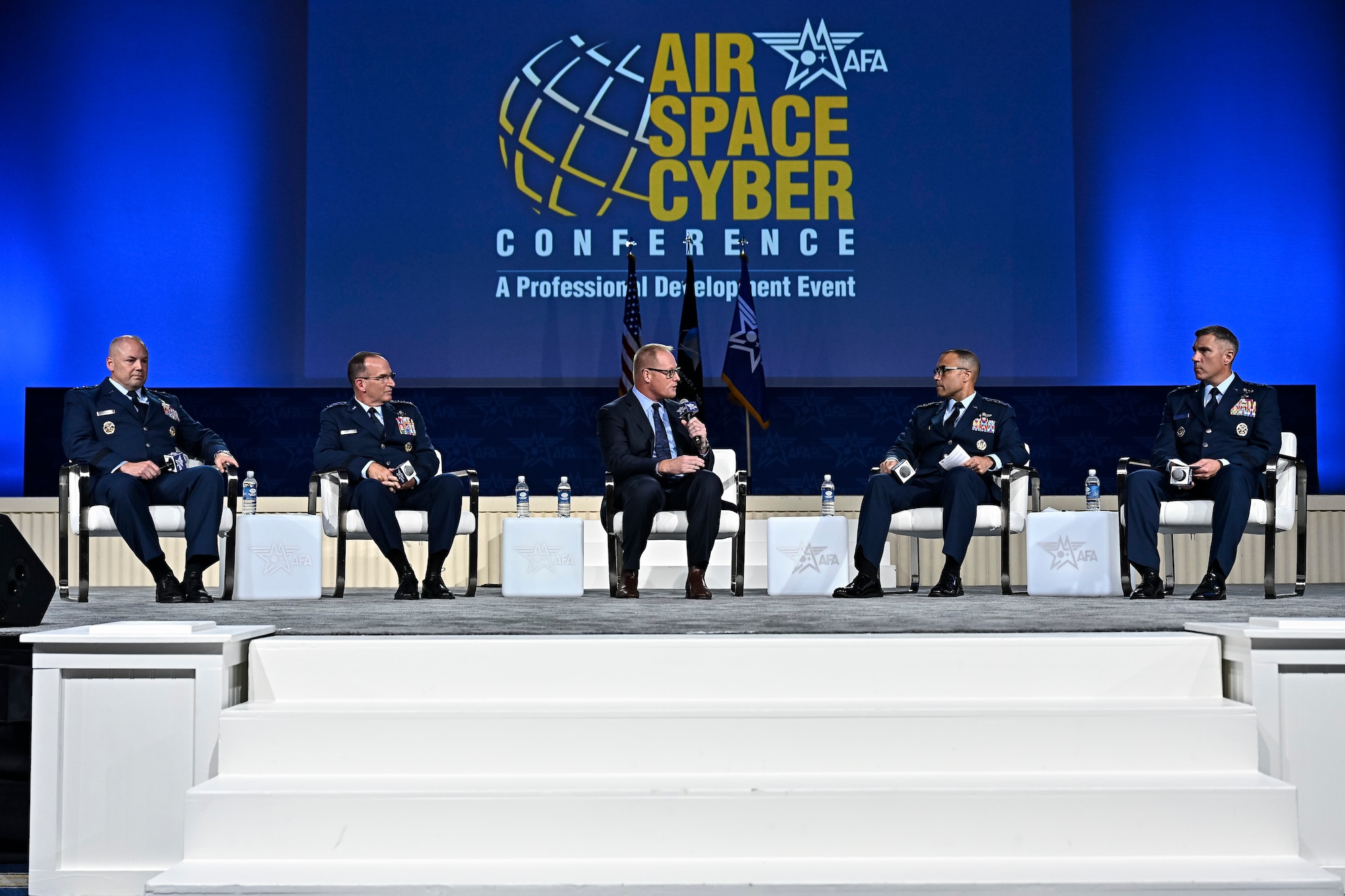A group of individuals sit in chairs on a stage.