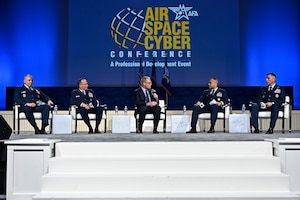 A group of individuals sit in chairs on a stage.