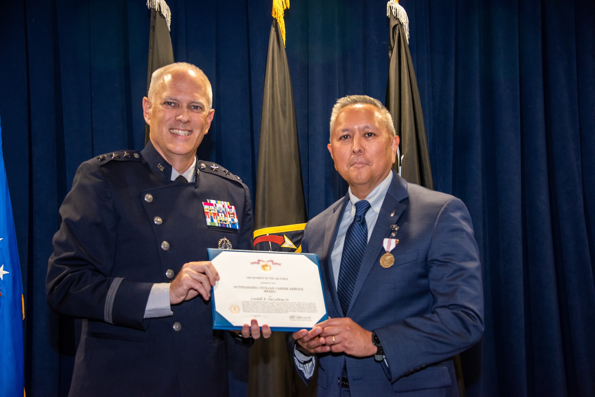 U.S. Space Force Lt. Gen. Philip Garrant, commander of Space Systems Command, presents Mr. Cordell A. DeLaPena Jr., program executive officer (PEO) for Military Communications and Positioning, Navigation, and Timing (MILCOMM & PNT) at SSC, with the Department of the Air Force Outstanding Civilian Career Service Award during DeLaPena’s retirement at Los Angeles Air Force Base, El Segundo, Calif., August 28, 2025. DeLaPena’s retirement comes after a distinguished career spanning four decades of service the nation, with his role at SSC leaving behind a legacy of fostering strong partnerships with industry, academia, and international allies, leveraging their expertise to accelerate innovation and deliver superior capabilities. (U.S. Space Force photo by Jason Slawson).