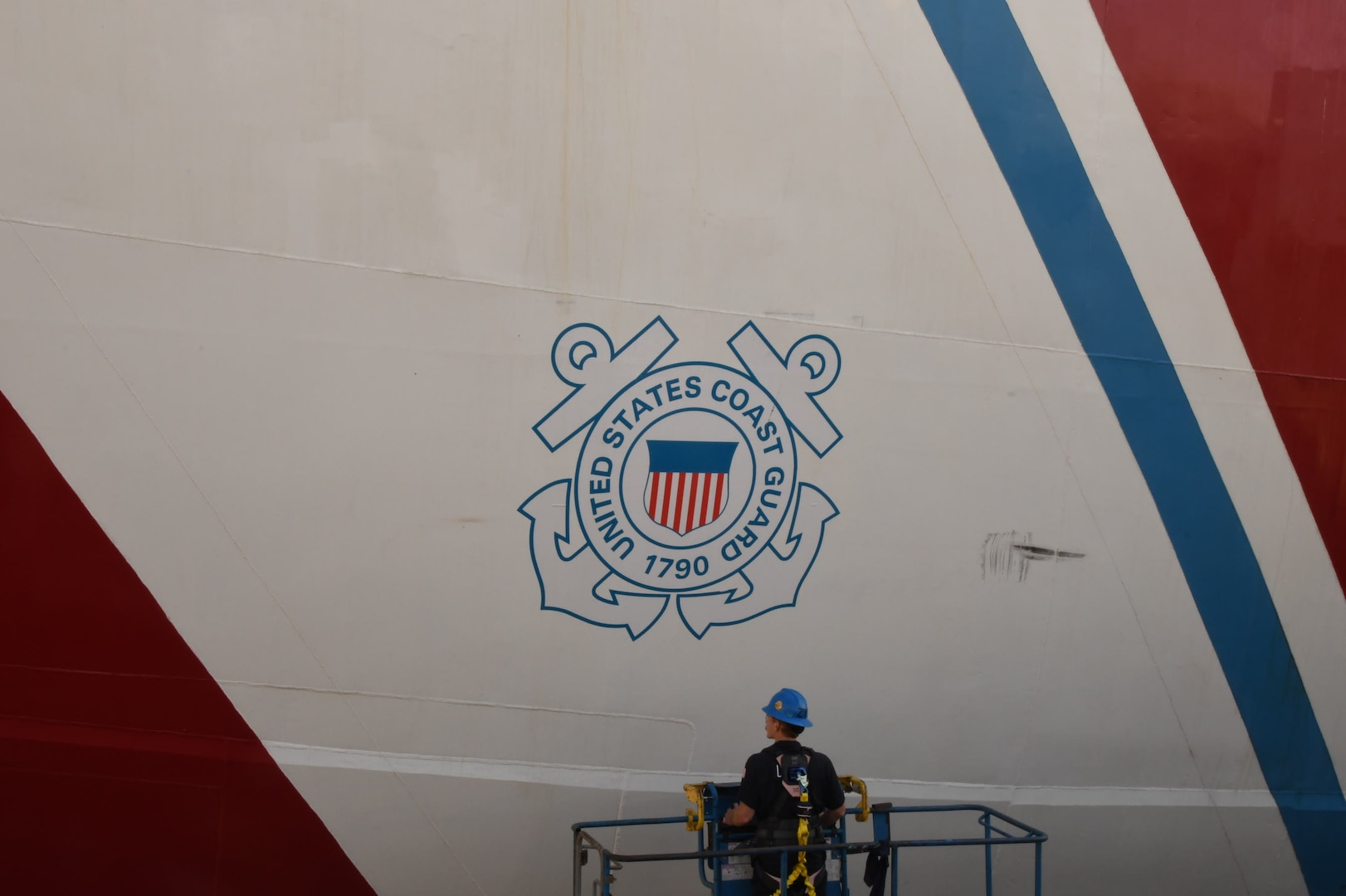 A USCGC Polar Star (WAGB 10) crewmember paints the racing stripe on the hull of the cutter in Vallejo, Calif., Aug. 1, 2025. Additional major work completed includes removing the centerline shaft for servicing and inspection, exchanging all three propellers, and renewing both forward and aft main deck surfaces. (U.S. Coast Guard photo by Seaman Reagan Vasbinder)
