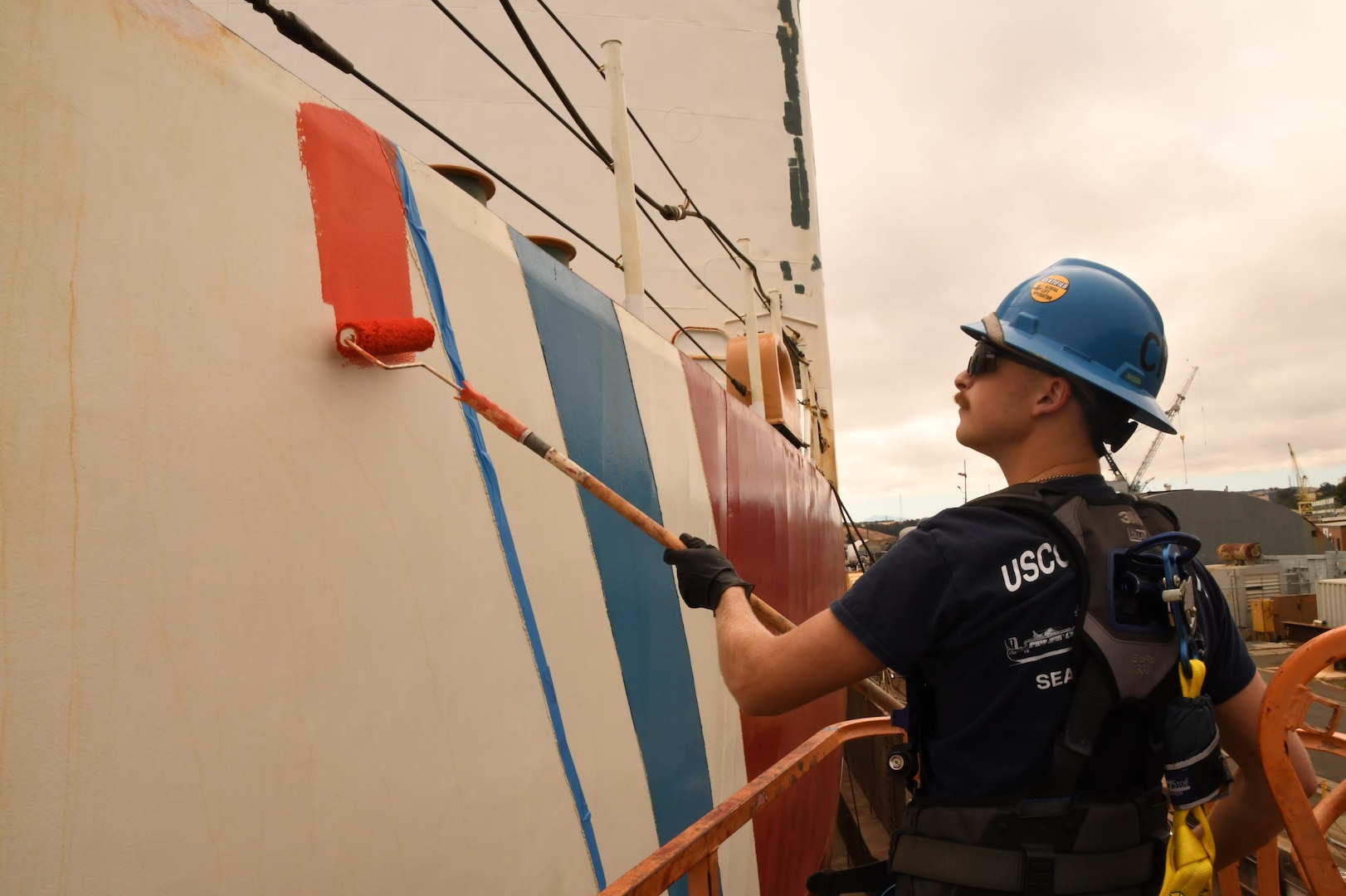 A USCGC Polar Star (WAGB 10) crewmember repaints the racing strip while the cutter is in a Vallejo, Calif., dry dock, Aug. 1, 2025. Additional major work completed includes removing the centerline shaft for servicing and inspection, exchanging all three propellers, and renewing both forward and aft main deck surfaces. (U.S. Coast Guard photo by Seaman Reagan Vasbinder)