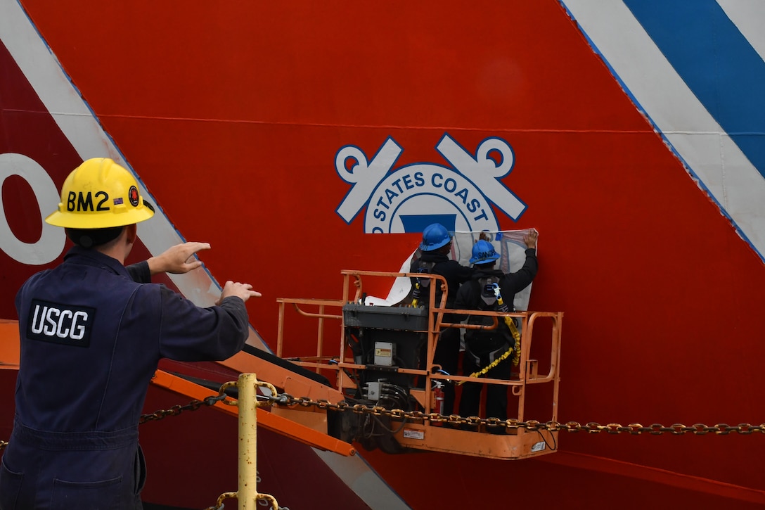 A boatswain’s mate assists the crewmembers of the USCGC Polar Star (WAGB 10) in helping paint the racing stripe on the hull of the cutter in Vallejo, Calif., Aug. 1, 2025. Additional major work completed includes removing the centerline shaft for servicing and inspection, exchanging all three propellers, and renewing both forward and aft main deck surfaces. (U.S. Coast Guard photo by Seaman Reagan Vasbinder)