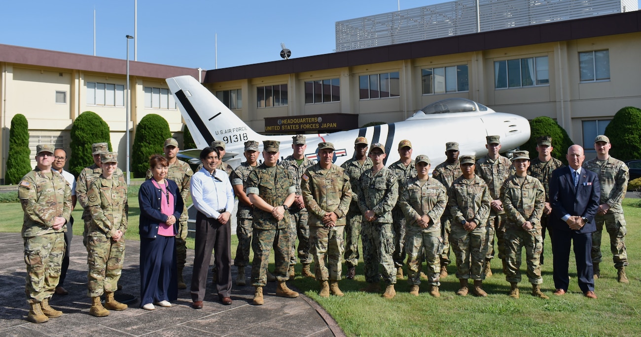 U.S. Military human resources personnel stationed in Japan and Hawaii pose for a group photo in front of the U.S. Forces Japan headquarters building during a theater human resource symposium hosted by the USFJ J1 staff on Yokota Air Base, Sept. 16, 2025.