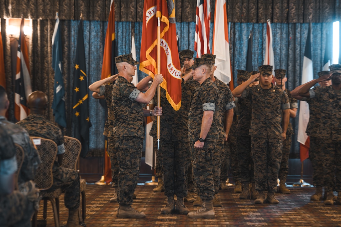 U.S. Marine Corps Brig. Gen. Robert B. Brodie, the incoming commanding officer of 3D Marine Expeditionary Brigade (3D MEB), left, receives the organizational colors from Brig. Gen. Trevor Hall, the outgoing commanding officer of 3D MEB, right, during the 3D MEB change of command ceremony at Camp Butler Officers’ Club, Okinawa, Japan, July 31, 2025. The ceremony marked the formal transfer of authority from Hall to Brodie. Hall is a native of Georgia and Brodie is a native of Pennsylvania. (U.S. Marine Corps photo by Cpl. Diego Garcia)