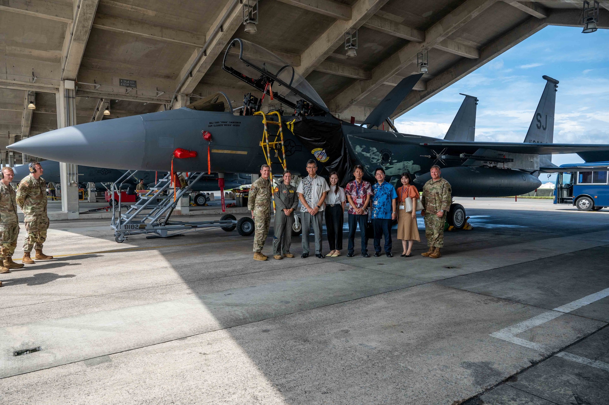 U.S. Air Force Brig. Gen. John Gallemore, left, 18th Wing commander, and Chief Master Sgt. William Cupp, 18th Wing command chief, stand for a photo with Mr. Masaru Murai, Okinawa Defense Bureau director general, and his staff in front of an F-15E Strike Eagle during a familiarization tour at Kadena Air Base, Sept. 11, 2025.