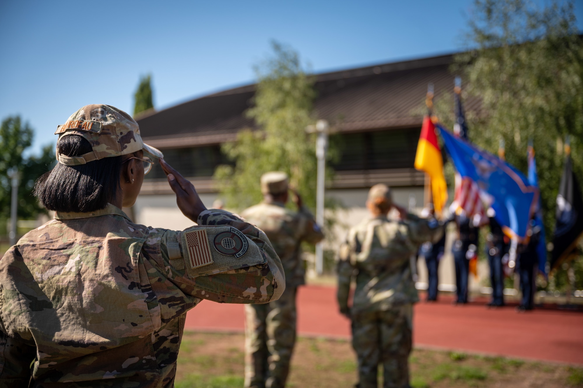 Airmen salute during the national anthem during a POW/MIA remembrance ceremony