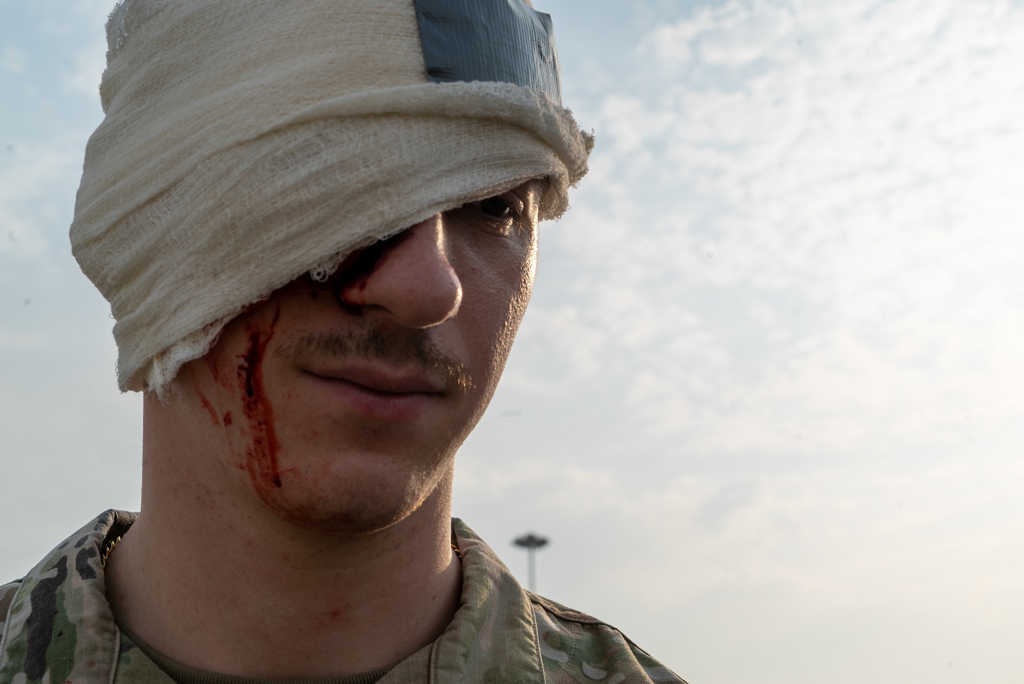 Senior Airman Omelczuk stands left of frame with his head bandaged from a simulated wound