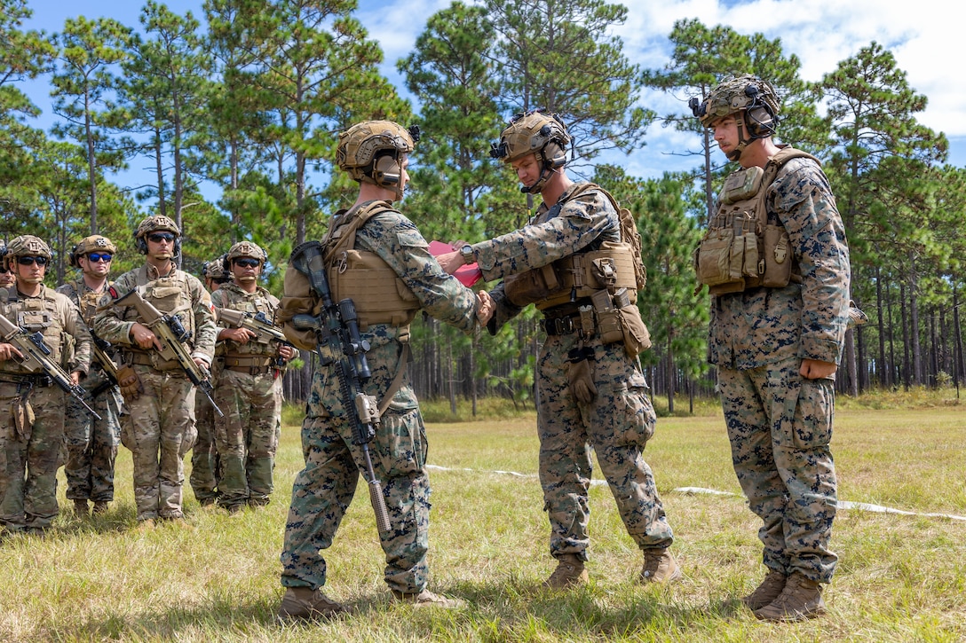U.S. Marine Corps Lance Cpl. Luke Fitch, left, a rifleman and native of Florida, is handed his re-enlistment citation by 1st Lt. Benjamin Watson, an infantry officer and native of South Carolina, with 2nd Battalion, 2nd Marine Regiment, alongside participating marines with Cuerpo de Infantreria de Marina (Chilean marine corps) during a multinational marksmanship range as part of exercise UNITAS 2025 at Marine Corps Base Camp Lejeune, North Carolina, Sept. 23, 2025. UNITAS, which is Latin for “unity,” was conceived in 1959 and has taken place annually since first conducted in 1960. This marks the 66th iteration of the world’s longest running annual multinational maritime exercise. (U.S. Marine Corps photo by Lance Cpl. Jack Labrador)