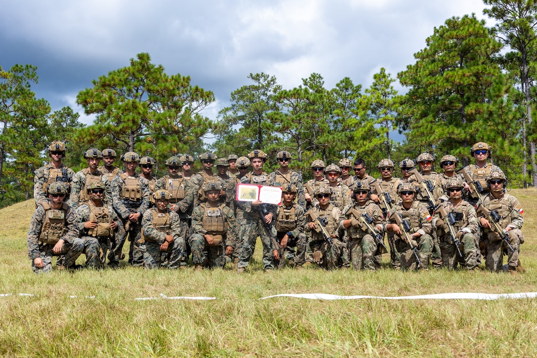 U.S. Marine Corps Lance Cpl. Luke Fitch, center, a rifleman with 2nd Battalion, 2nd Marine Regiment, and native of Florida, poses for a photo with U.S. Marines with 2nd Bn., 2nd Marines, and marines with Cuerpo de Infantreria de Marina (Chilean marine corps) after his reenlistment ceremony during a multinational marksmanship range as part of exercise UNITAS 2025 at Marine Corps Base Camp Lejeune, North Carolina, Sept. 23, 2025. UNITAS, which is Latin for “unity,” was conceived in 1959 and has taken place annually since first conducted in 1960. This marks the 66th iteration of the world’s longest running annual multinational maritime exercise. (U.S. Marine Corps photo by Lance Cpl. Jack Labrador)
