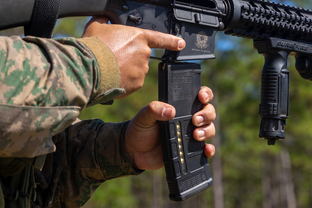 A marine with Corpo de Fuzileiros Navais (Brazilian marine corps) loads a magazine into his weapon during a multinational marksmanship range as part of exercise UNITAS 2025 at Marine Corps Base Camp Lejeune, North Carolina, Sept. 23, 2025. UNITAS, which is Latin for “unity,” was conceived in 1959 and has taken place annually since first conducted in 1960. This marks the 66th iteration of the world’s longest running annual multinational maritime exercise. (U.S. Marine Corps photo by Lance Cpl. Jack Labrador)