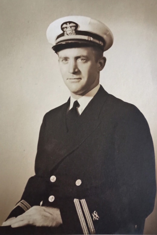 A man in a military dress uniform poses in an old black and gray photo.