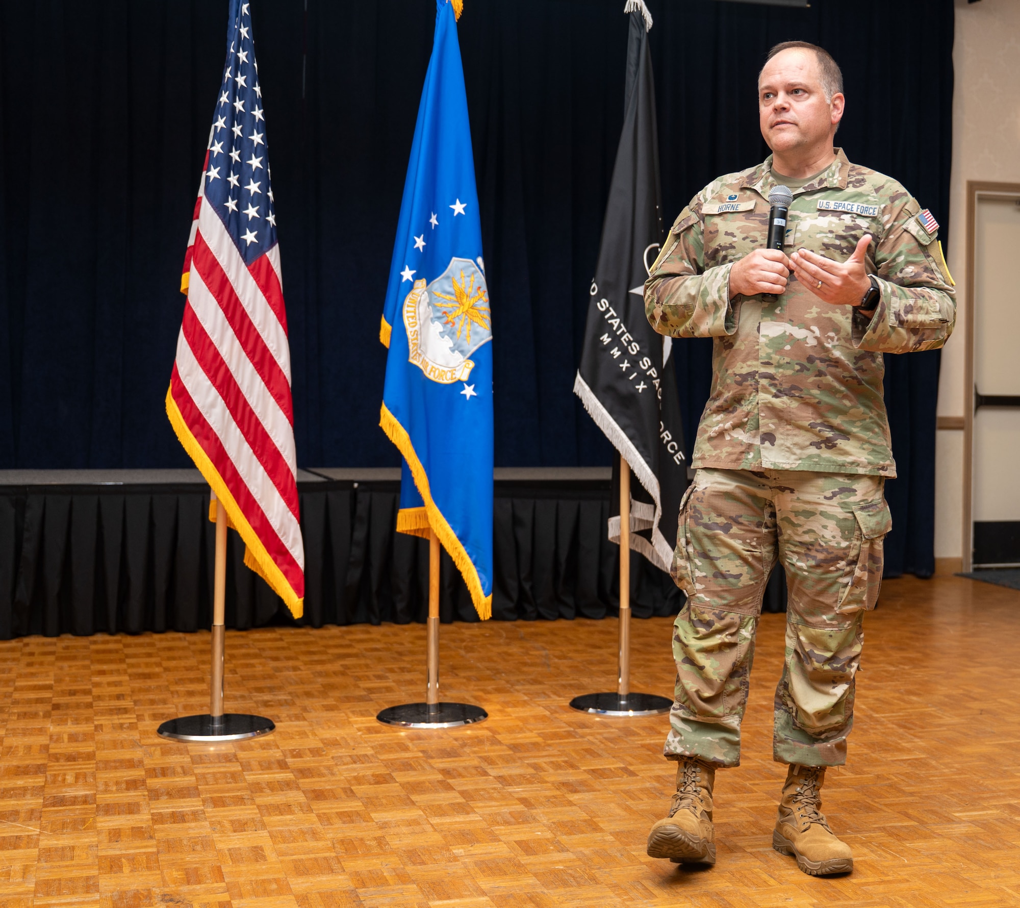 Man stands, talking and gesturing to a crowd of people.