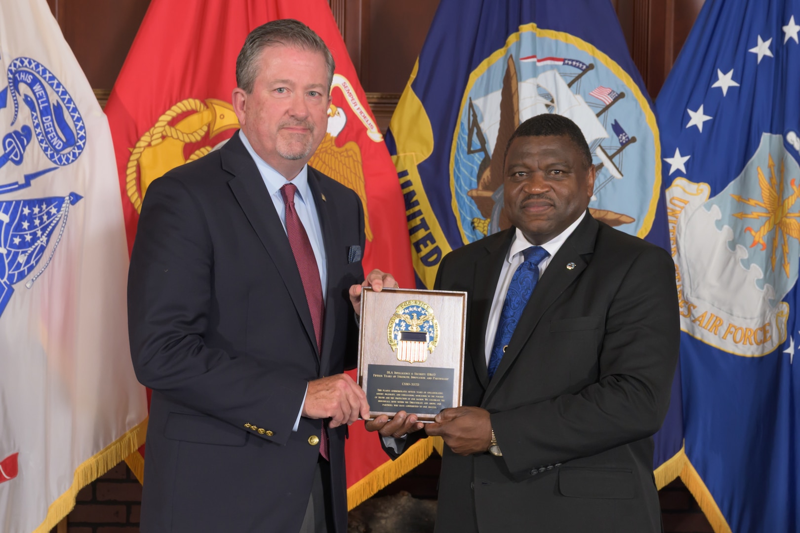 Two men pose holding a plaque.
