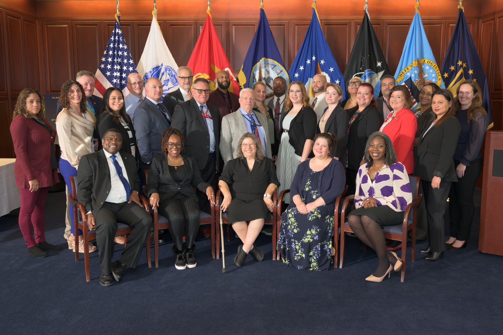 A group of people pose in front of flags.