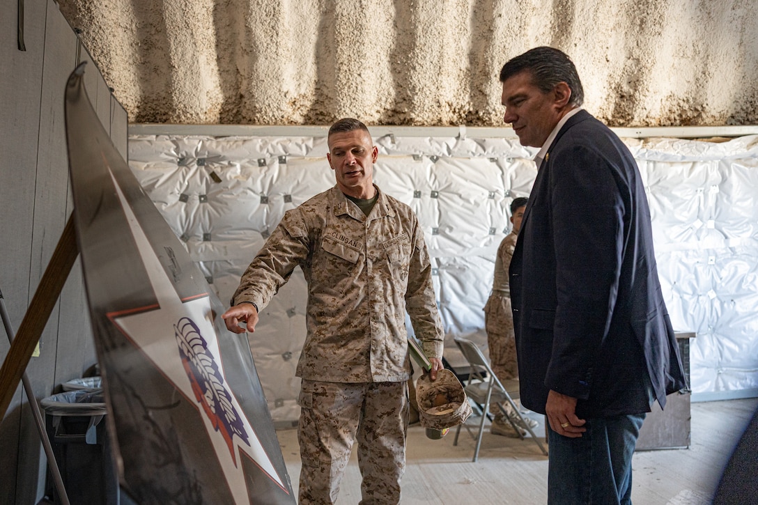 U.S. Marine Corps Maj. Gen. Mark Clingan, commanding general of Marine Air Ground Task Force Training Command, Marine Corps Air-Ground Combat Center, center, and Rep. Jay Obernolte, a California native, discuss origins of the 6th Marines insignia during a visit to the 6th Marines Regimental Combat Operations Center at MCAGCC, Twentynine Palms, California, Aug. 13, 2025. The tour of the 6th Marines COC demonstrated how Service Level Training Exercise 4-25 is designed to challenge Marines in a realistic training environment while producing combat-ready forces capable of operating as an integrated Marine Air Ground Task Force. (U.S. Marine Corps photo by Lance Cpl. Enge You)