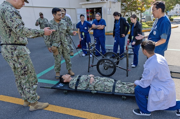 YOKOSUKA, Japan (Sept. 23, 2025) – Hospital corpsmen and staff from U.S. Navy Medicine Readiness and Training Command (USNMRTC) Yokosuka demonstrate the use of a wheeled litter carrier during a mass casualty drill. The exercise tested the command’s ability to triage, treat and transport multiple simulated patients during a crisis. (U.S. Navy photo by Daniel Taylor/USNMRTC Yokosuka Public Affairs)