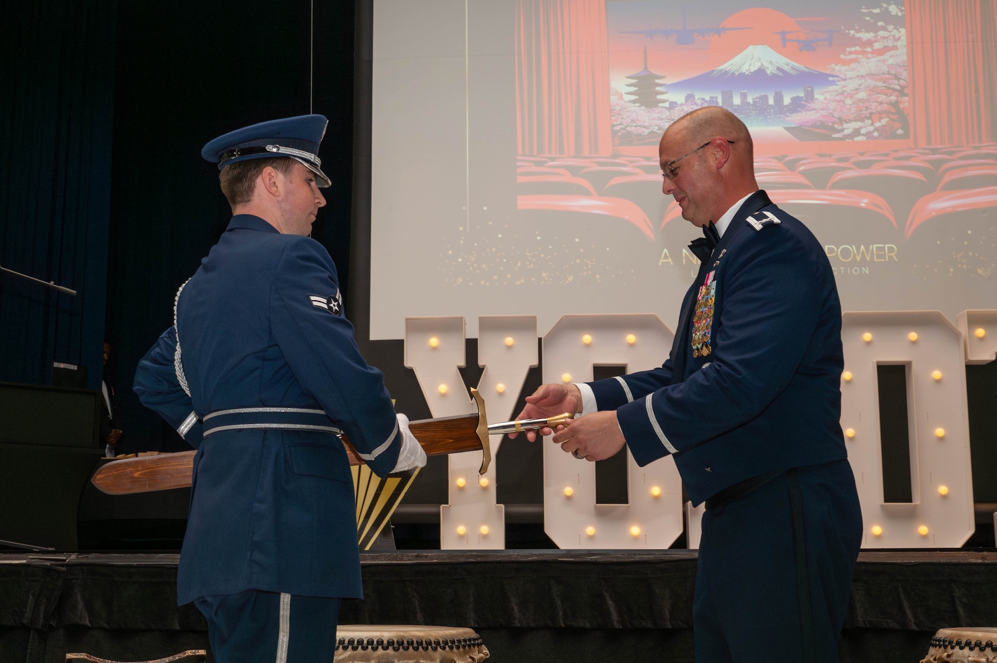From left, U.S. Air Force Airman 1st Class Tyler McGahee, Yokota Air Base Honor Guardsman, presents the 374th Airlift Wing sword to Col. Richard McElhaney, 374 AW commander.