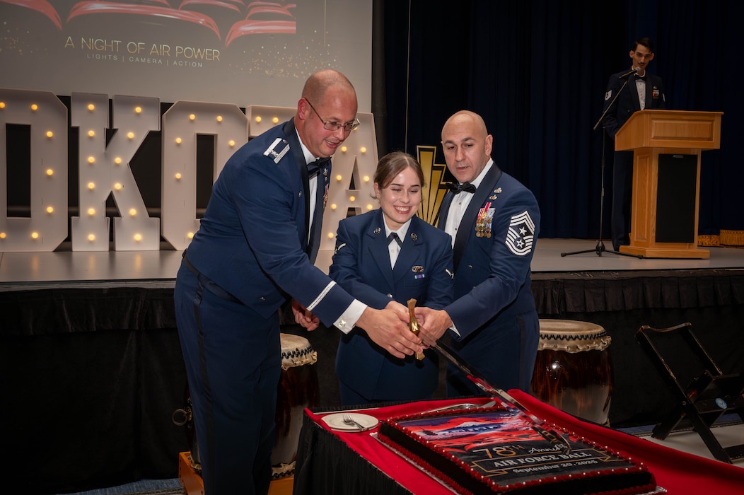 From left, U.S. Air Force Col. Richard McElhaney, 374th Airlift Wing commander, Amn. Kayla Karelas, 374 AW public affairs apprentice, and Chief Master Sgt. Kenneth Hauck, 374 AW command chief, cut the ceremonial cake.