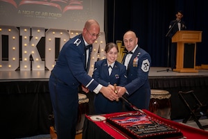 From left, U.S. Air Force Col. Richard McElhaney, 374th Airlift Wing commander, Amn. Kayla Karelas, 374 AW public affairs apprentice, and Chief Master Sgt. Kenneth Hauck, 374 AW command chief, cut the ceremonial cake.