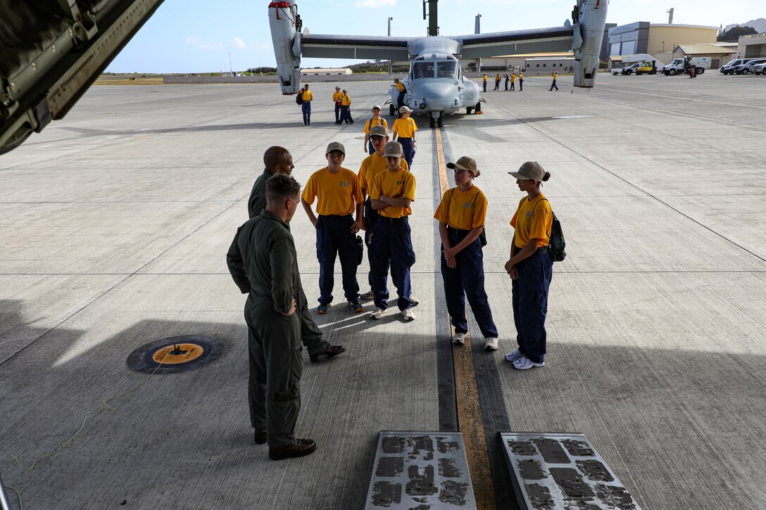 Naval Junior ROTC cadets of Kalaheo High School listen as they receive information during a static display presentation at Marine Corps Air Station Kaneohe Bay, Hawaii, Sept. 12, 2025.  The visit gave the NJROTC cadets a comprehensive look at how a military aviation unit operates through the various roles and responsibilities from mechanical maintenance to flight operations. (U.S. Marine Corps photo by Staff Sgt. Heather Atherton)