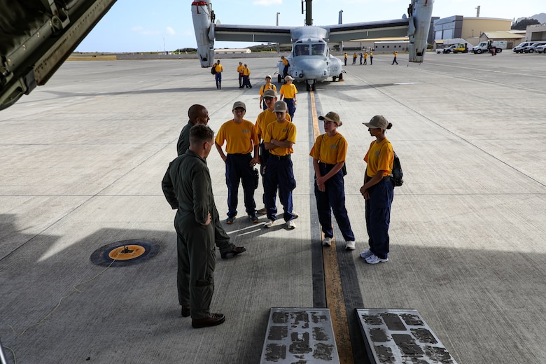 Naval Junior ROTC cadets of Kalaheo High School listen as they receive information during a static display presentation at Marine Corps Air Station Kaneohe Bay, Hawaii, Sept. 12, 2025.  The visit gave the NJROTC cadets a comprehensive look at how a military aviation unit operates through the various roles and responsibilities from mechanical maintenance to flight operations. (U.S. Marine Corps photo by Staff Sgt. Heather Atherton)