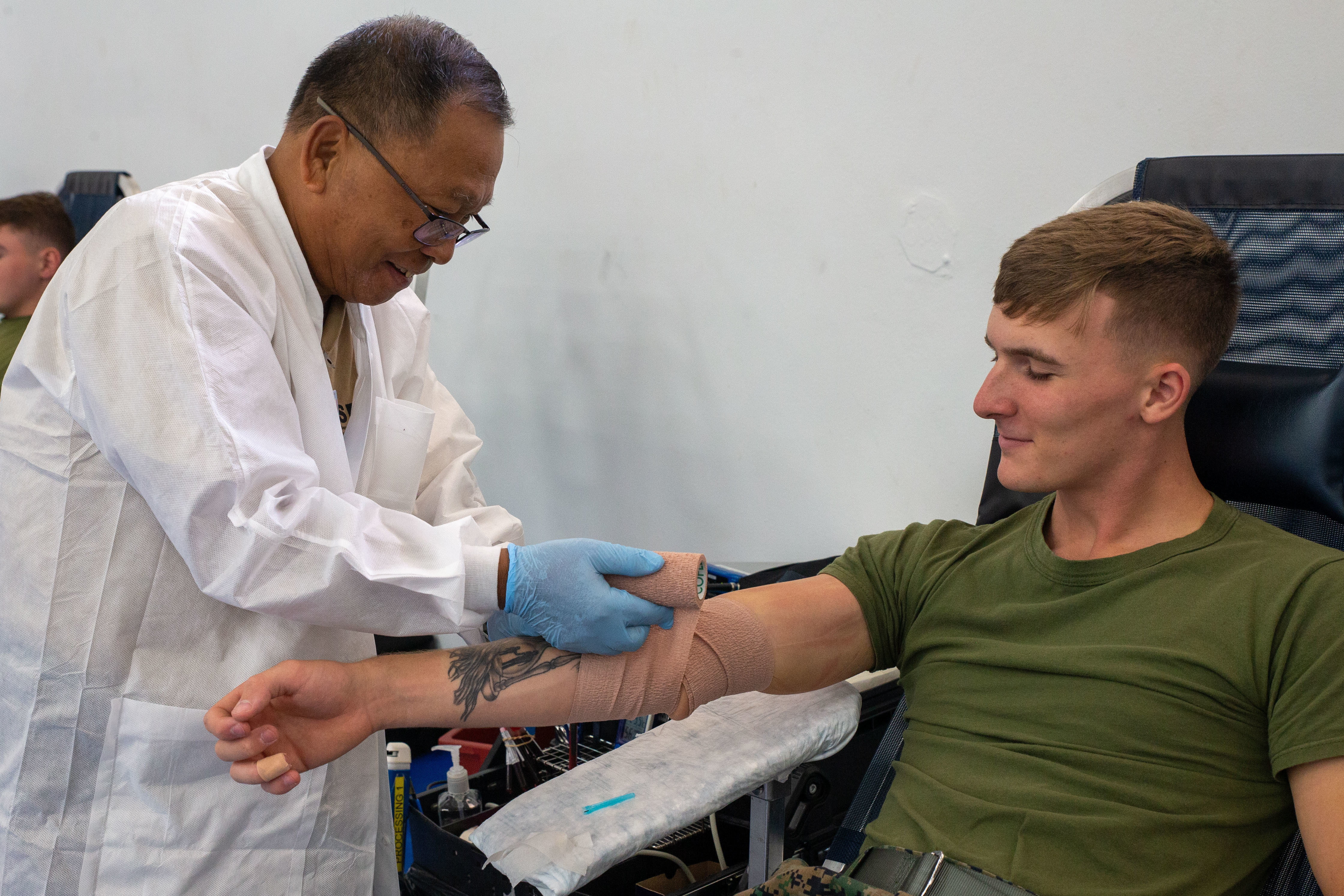 Retired U.S. Army Sgt. 1st Class Elpidio Patague, phlebotomist, Naval Hospital Guam, wraps up U.S. Marine Corps Cpl. Braiden Grissom, data systems administrator, Marine Corps Base Camp Blaz, with a bandage after donating blood during a blood drive on MCB Camp Blaz, Guam, Sept. 24, 2025. Camp Blaz partnered with Armed Services Blood Program Donor Center Guam and Naval Hospital Guam to help host a blood drive. (U.S. Marine Corps photo by Lance Cpl. Afton Smiley)