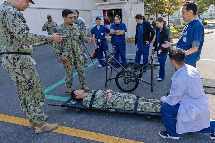 YOKOSUKA, Japan (Sept. 23, 2025) – Hospital corpsmen and staff from U.S. Navy Medicine Readiness and Training Command (USNMRTC) Yokosuka demonstrate the use of a wheeled litter carrier during a mass casualty drill. The exercise tested the command’s ability to triage, treat and transport multiple simulated patients during a crisis. (U.S. Navy photo by Daniel Taylor/USNMRTC Yokosuka Public Affairs)