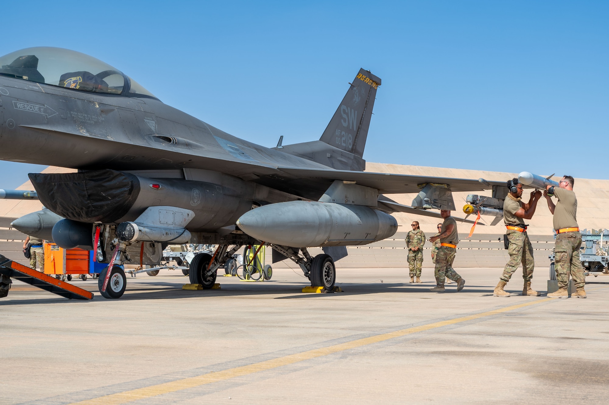 U.S. Airmen assigned to the 79th Expeditionary Fighter Generation Squadron load an AIM-120, while evaluators watch their performance during a load competition.