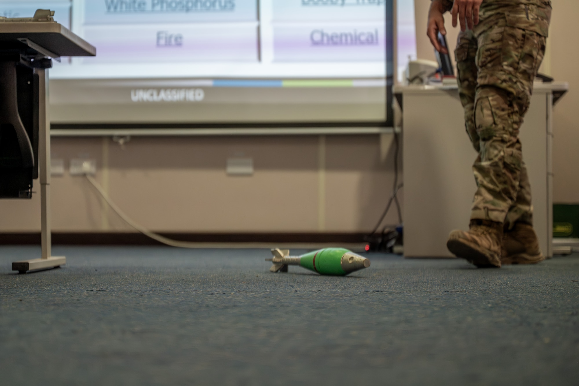 An inert 81mm white phosphorus mortar lays on the ground