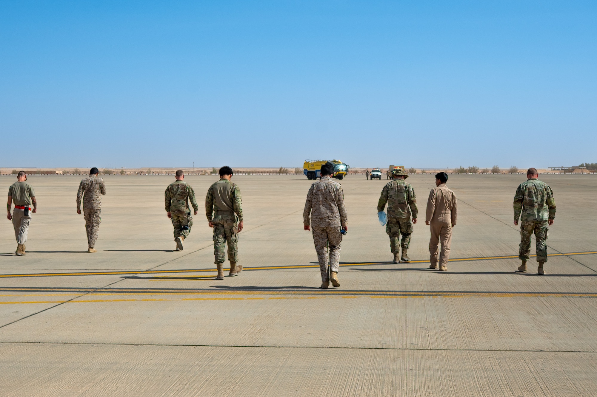 USAF and RSAF service members walk across a flightline