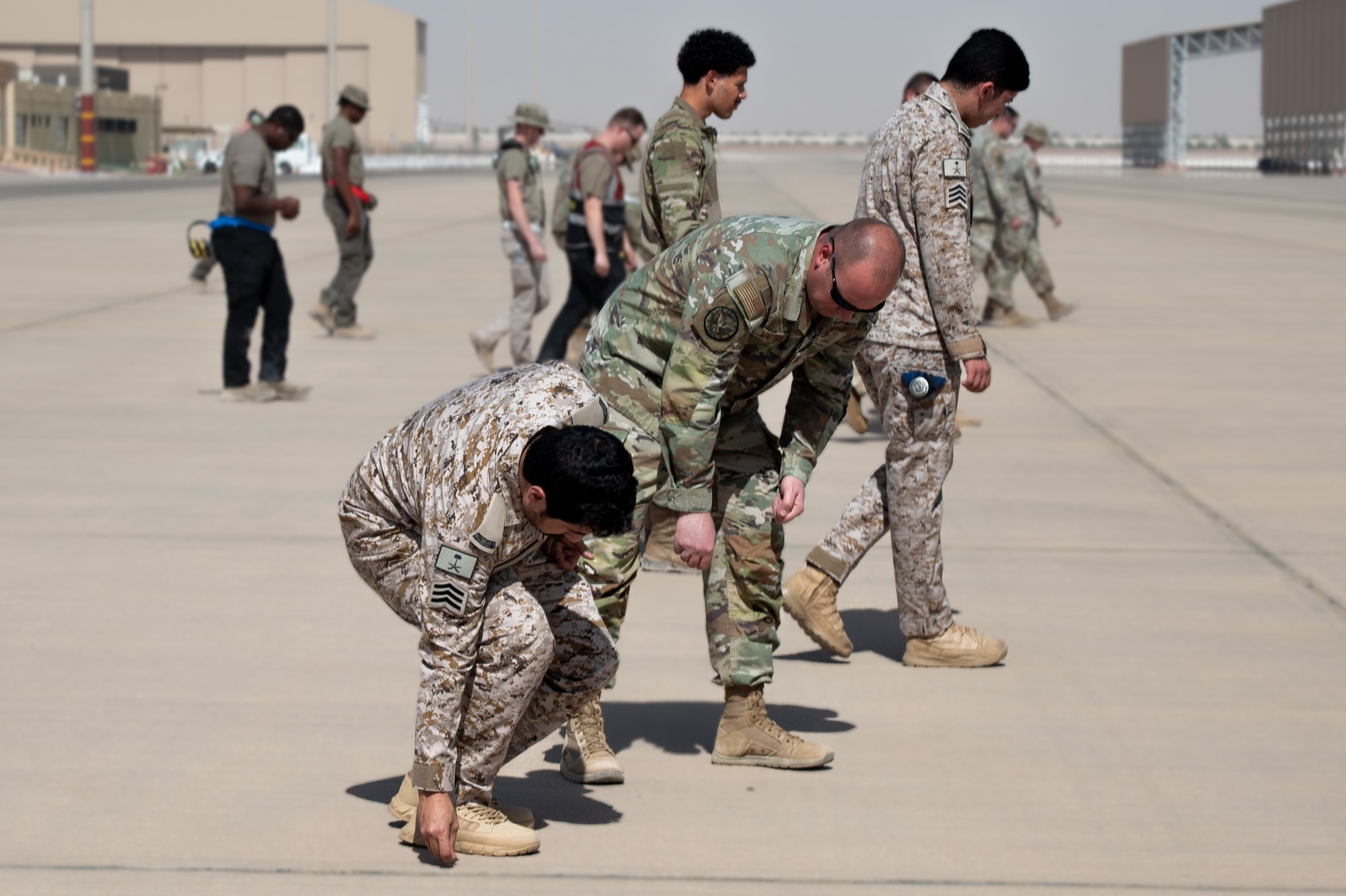 USAF and RSAF service members pick up foreign object debris on a flightline