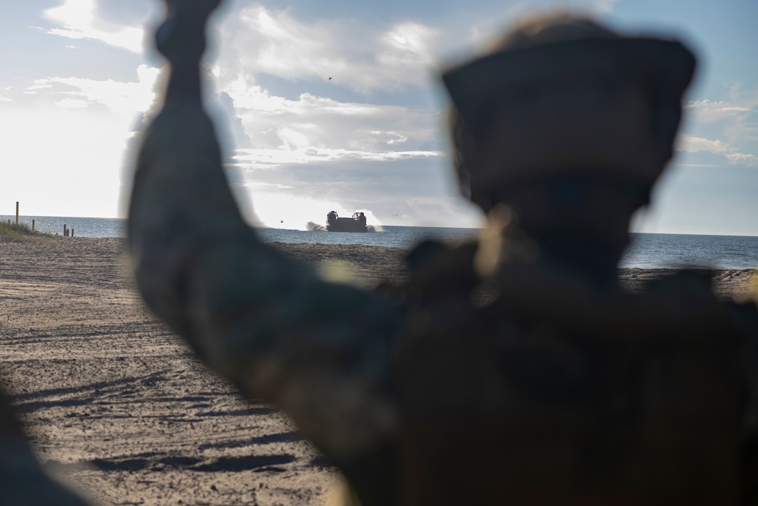 U.S. Navy Petty Officer 2nd Class Chad Brady, a member of the beach landing crew, directs a U.S. Navy landing craft, air cushion assigned to Assault Craft Unit 4 onto Onslow Beach during exercise UNITAS 2025 at Marine Corps Base Camp Lejeune, North Carolina, Sept. 25, 2025. UNITAS, Latin for “unity,” was conceived in 1959 and has taken place annually since 1960. This year marks the 66th iteration of the world’s longest-running multinational maritime exercise. (U.S. Marine Corps photo by Lance Cpl. Payton Goodrich)