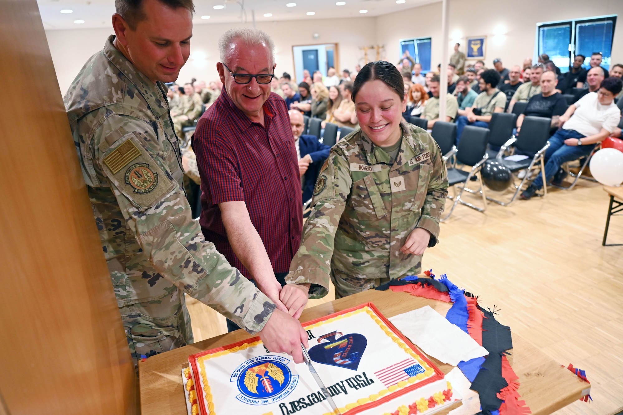 Lt. Col. Christopher Cagle, 435th Construction and Training Squadron commander, cuts a cake with two members of the squadron during the 75th anniversary celebration of the 435th CTS, Sept. 19, 2025.  Mr. Claus Steffes is the longest serving member of the squadron, with 44 years of service, along with Staff Sgt. Monica Romero, who has been in the squadron 17 days. (U.S. Air Force photo by Capt. Lou Burton)