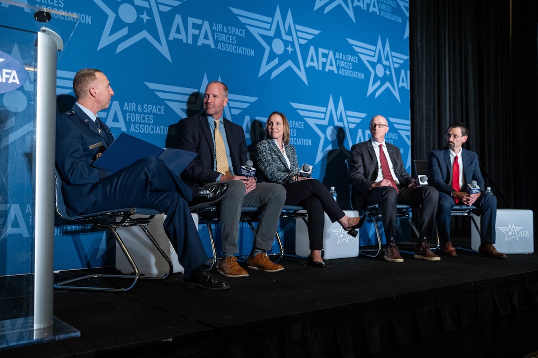STARCOM leadership in uniform on stage with other panel guests. Speakers and listeners are sitting in chairs.