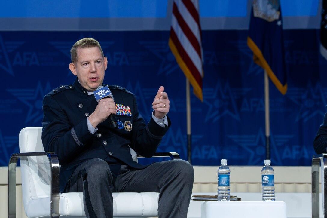 STARCOM leadership in uniform on stage with other panel guests. Speakers and listeners are sitting in chairs.