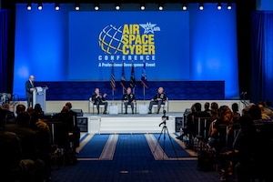 STARCOM leadership in uniform on stage with other panel guests. Speakers and listeners are sitting in chairs.