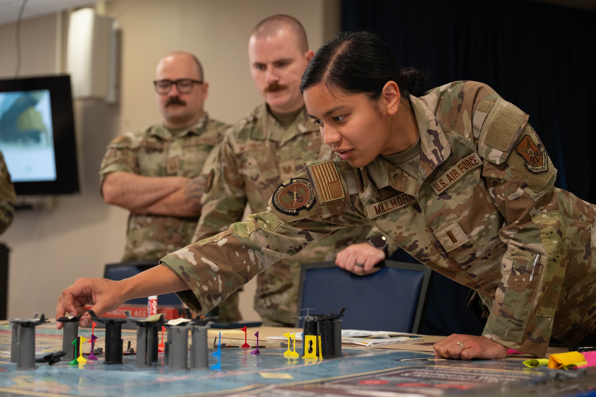 U.S. Air Force 2nd Lt. Alyssa Millhorn, 7th Logistics Readiness Squadron maintenance support officer in charge, moves a board piece during a war gaming tabletop exercise at Dyess Air Force Base, Texas, Sept. 16, 2025. The board wargame was being played to train mission planning, communication and coordination across multiple domains. (U.S. Air Force photo by Airman William Neal)