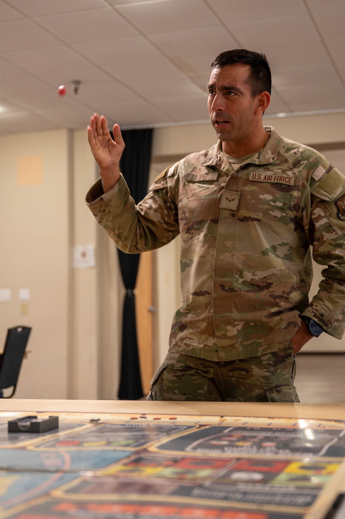 U.S. Air Force Airman 1st Class Javier Lopez, 9th Bomber Generation Squadron avionics technician, rolls a die during KingFish Agile Combat Employment board wargame exercise at Dyess Air Force Base, Texas, Sept. 16, 2025. KingFish ACE is an exercise that helps war fighters understand how to quickly, creatively and precisely use decision making skills that could be used in real life. (U.S. Air Force photo by Airman William Neal)