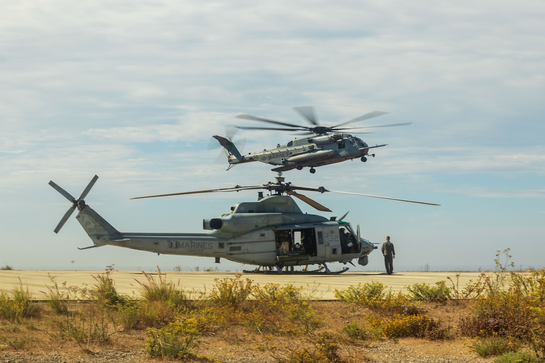 A UH-1Y Venom helicopter and a CH-53 Super Stallion with Marine Medium Tiltrotor Squadron (VMM) 163 (Reinforced), 11th Marine Expeditionary Unit, stage on a landing pad during a tactical recovery of aircraft and personnel course hosted by Expeditionary Operations Training Group, I Marine Expeditionary Force at Marine Corps Base Camp Pendleton, California, Sept. 18, 2025. The TRAP course is designed to develop the capabilities of Marines to recover aircraft, personnel and equipment in austere environments. (U.S. Marine Corps photo by Lance Cpl. Nicole Stuart)